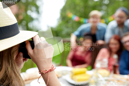 Image of woman photographing friends at summer garden party