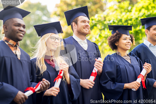 Image of happy students in mortar boards with diplomas