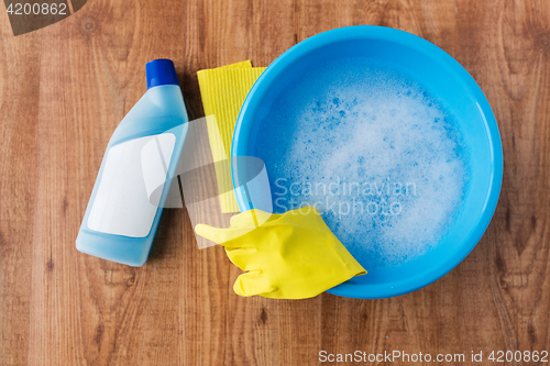 Image of basin with cleaning stuff on wooden background