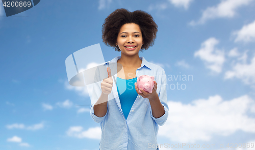 Image of happy woman with piggy bank showing thumbs up