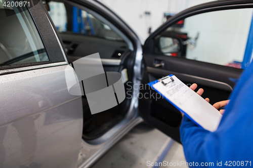 Image of auto mechanic man with clipboard at car workshop