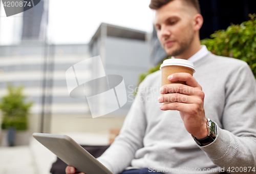 Image of man with tablet pc and coffee cup on city street