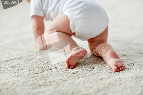 Image of little baby in diaper crawling on floor at home