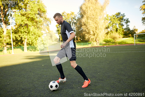 Image of soccer player playing with ball on football field