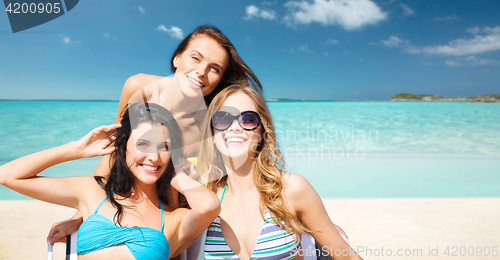 Image of happy women sunbathing in chairs on summer beach