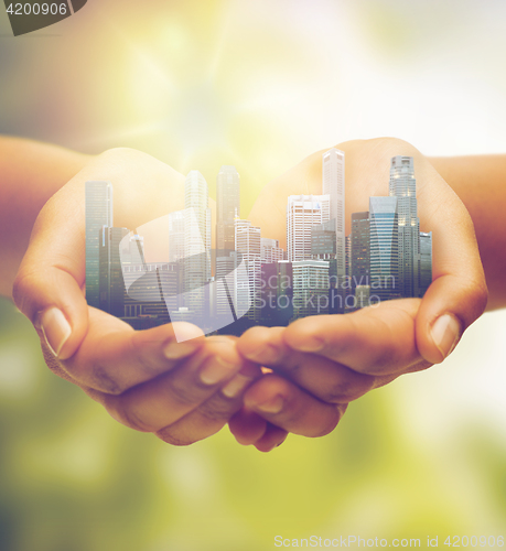 Image of hands holding city over green natural background