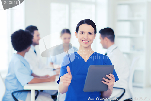 Image of happy doctor with tablet pc over team at clinic