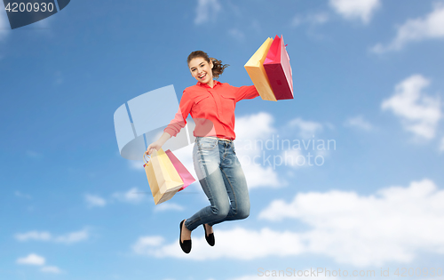 Image of smiling young woman with shopping bags jumping