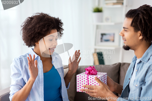 Image of happy couple with gift box at home