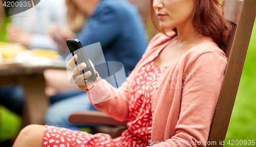 Image of woman with smartphone and friends at summer party