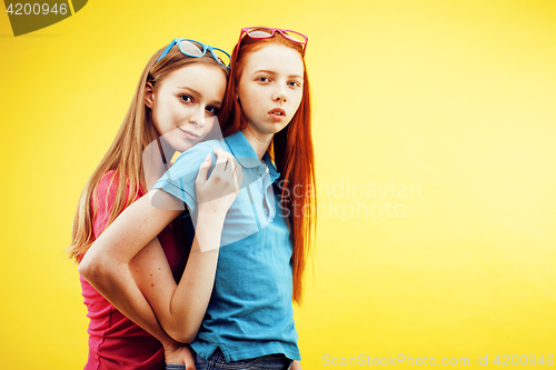 Image of lifestyle people concept: two pretty young school teenage girls having fun happy smiling on yellow background