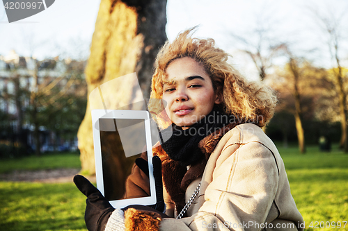 Image of young cute blond african american girl student holding tablet an