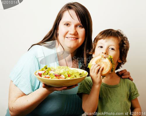 Image of mature woman holding salad and little cute boy with hamburger te