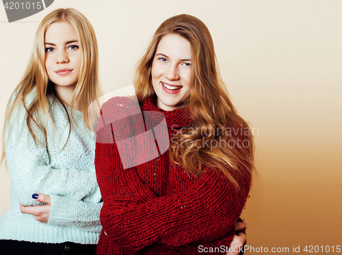 Image of Two young girlfriends in winter sweaters indoors having fun. Lif