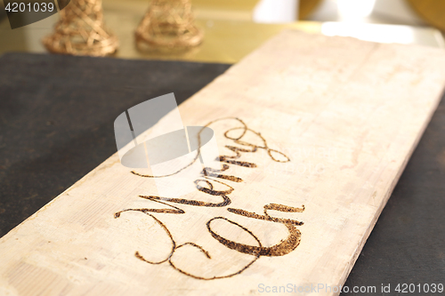 Image of Merry christmas, burning subtitles in wood