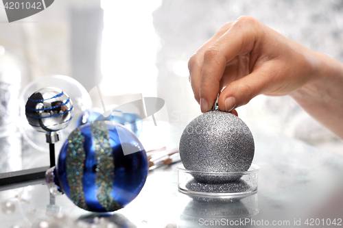 Image of Work on decorating Christmas baubles. A woman painting a design on a silver bauble Christmas star, Christmas decoration