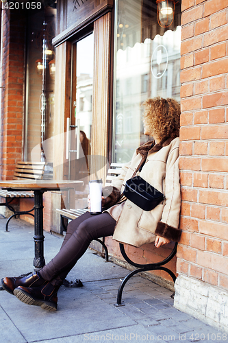 Image of young pretty african american women drinking coffee outside in c