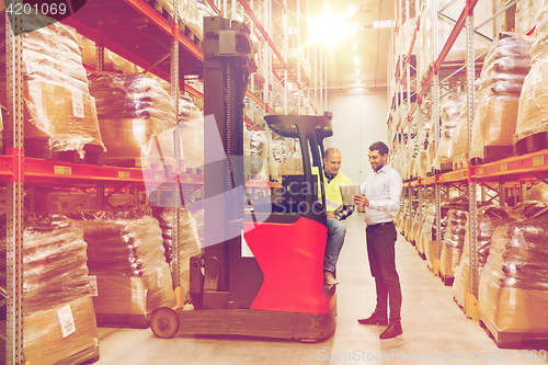 Image of men with tablet pc and forklift at warehouse