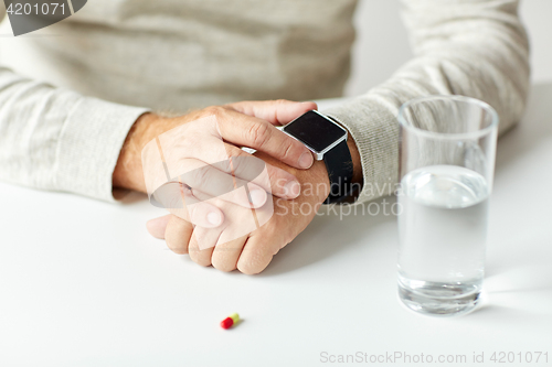 Image of close up of senior man with water, pill and watch