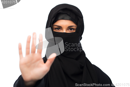 Image of muslim woman in hijab showing stop sign