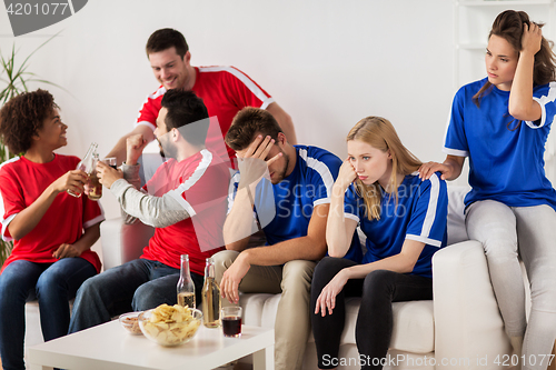 Image of friends or football fans watching soccer at home