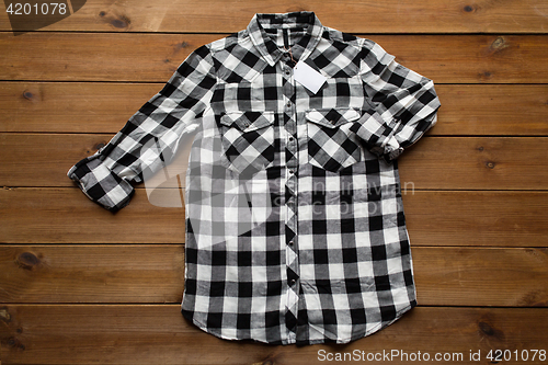 Image of checkered shirt with tag on wooden background