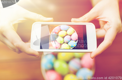 Image of close up of hands with easter eggs and smartphone