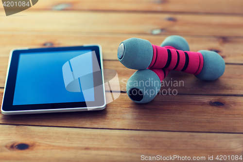 Image of close up of dumbbells and tablet pc on wood