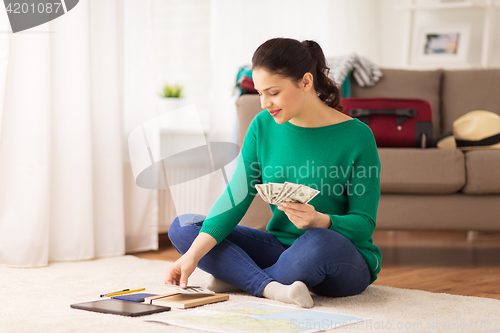 Image of happy woman with money and travel map at home