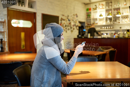 Image of young woman with smartphone at cafe