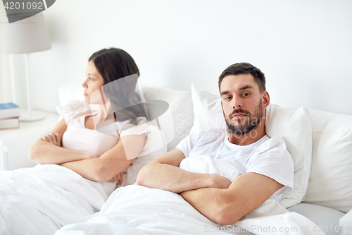 Image of unhappy couple having conflict in bed at home