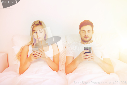 Image of couple with smartphones in bed