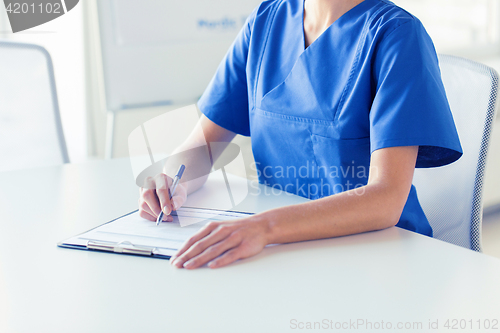 Image of close up of doctor or nurse writing to clipboard