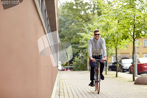 Image of young man riding bicycle on city street