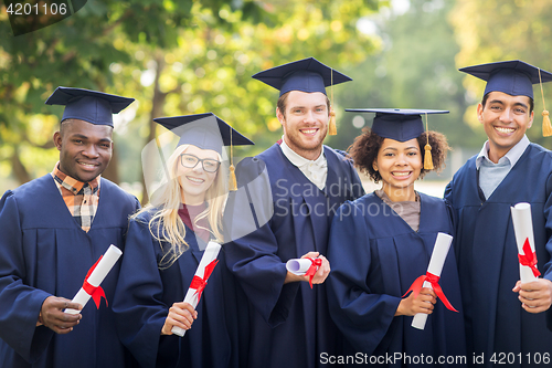 Image of happy students in mortar boards with diplomas