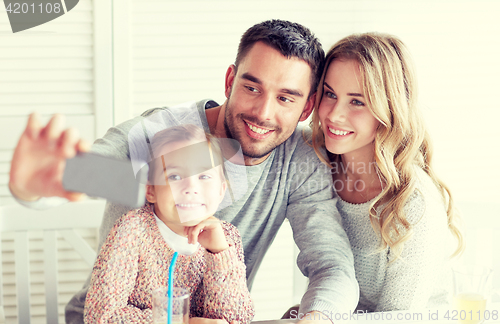 Image of happy family taking selfie at restaurant