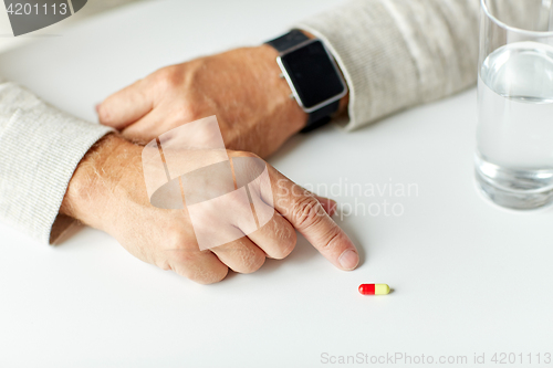 Image of close up of senior man with water, pill and watch