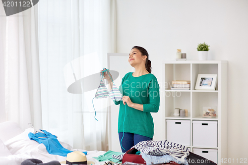 Image of woman with swimsuit packing travel bag at home