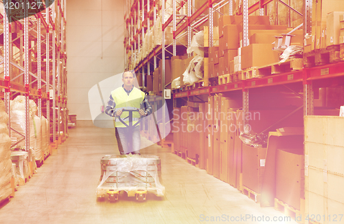 Image of man carrying loader with goods at warehouse