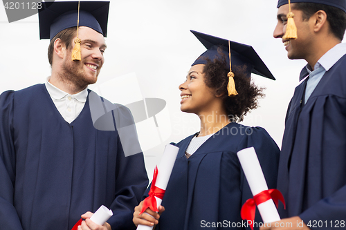 Image of happy students in mortar boards with diplomas