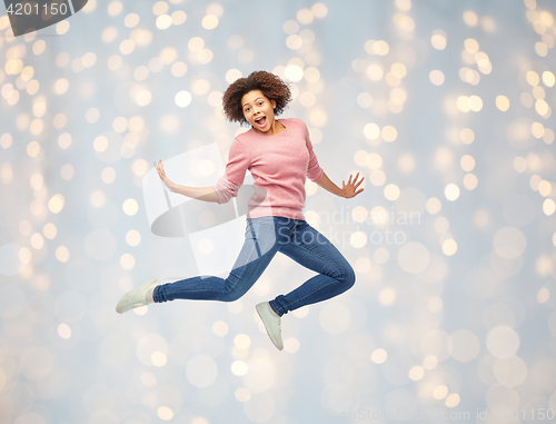 Image of happy african american woman jumping over white