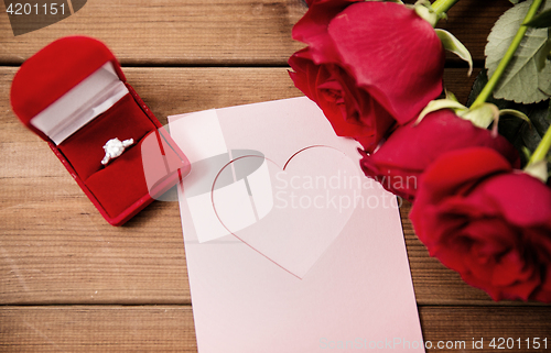 Image of close up of diamond ring, roses and greeting card