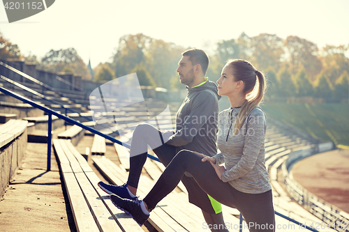 Image of couple stretching leg on stands of stadium