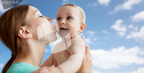 Image of happy mother kissing little baby over blue sky