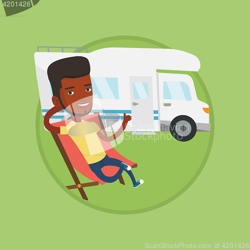 Image of Man sitting in chair in front of camper van.