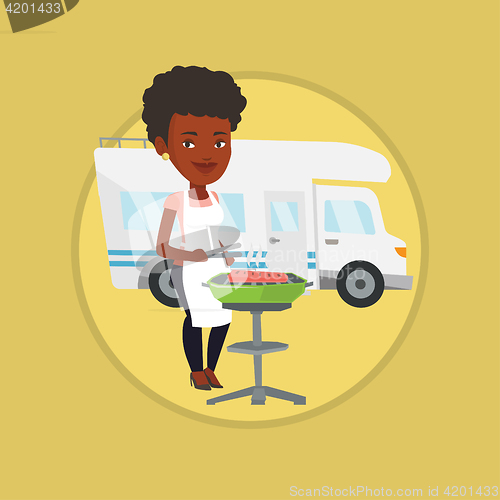 Image of Woman having barbecue in front of camper van.