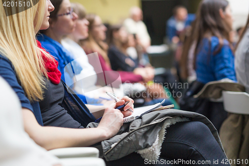 Image of Hands holding pens and making notes at conference lecture.
