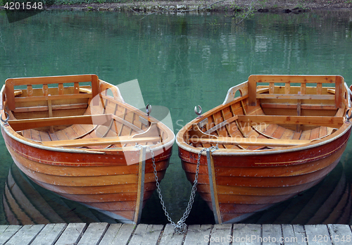Image of Rowboats parked in a row near a clear water lake
