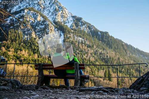 Image of Couple sitting on bench near mountains