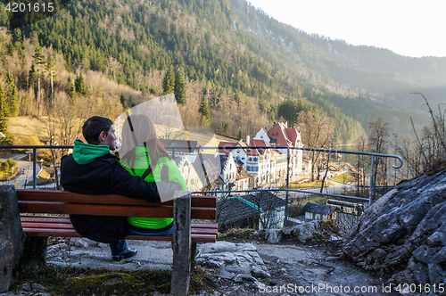 Image of Couple sitting on bench near mountains